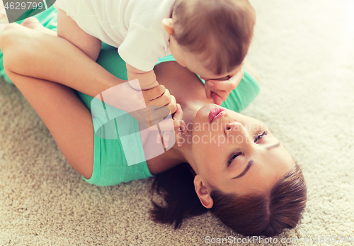 Image of happy mother playing with little baby at home