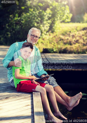 Image of grandfather and boy with tablet pc on river berth