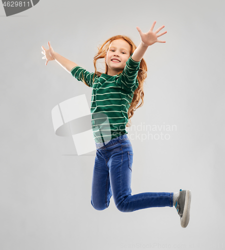 Image of smiling red haired girl in striped shirt jumping