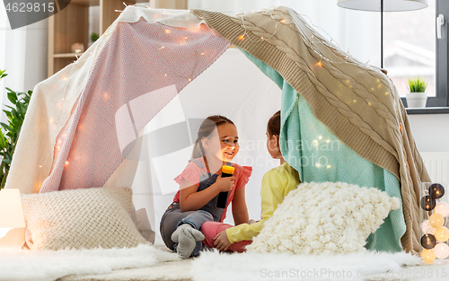 Image of girls playing with torch in kids tent at home