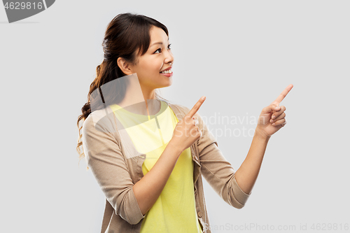 Image of happy asian woman pointing fingers up