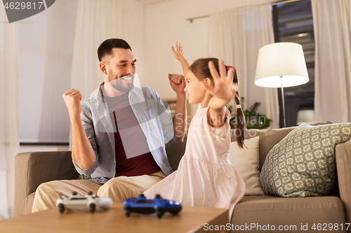 Image of father and daughter playing video game at home