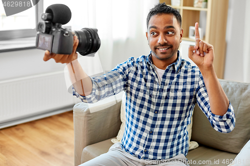 Image of male video blogger with camera blogging at home