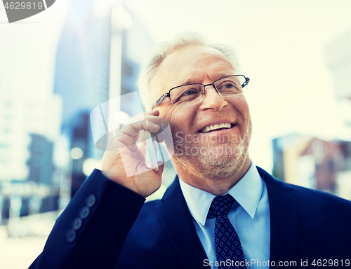 Image of smiling old businessman calling on smartphone