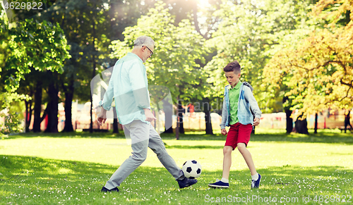 Image of old man and boy playing football at summer park