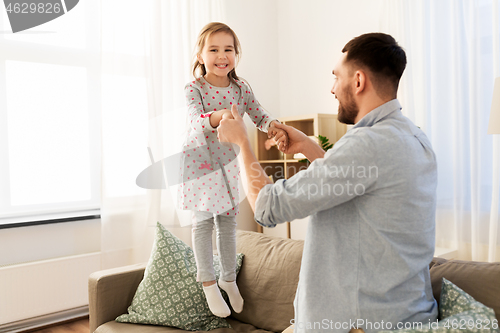 Image of father and daughter jumping and having fun at home