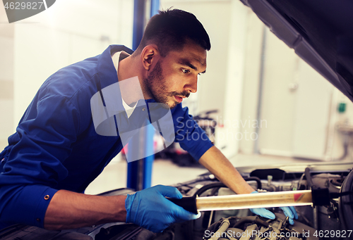 Image of mechanic man with lamp repairing car at workshop