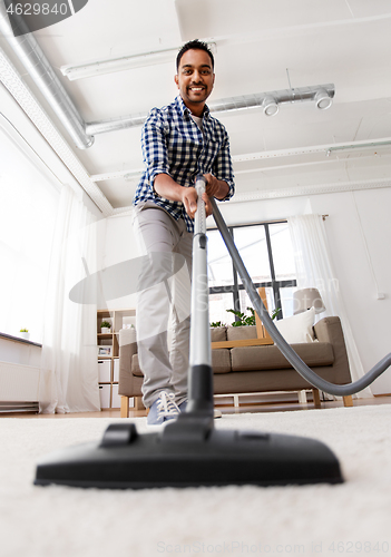 Image of indian man with vacuum cleaner at home