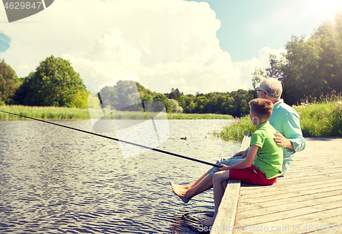 Image of grandfather and grandson fishing on river berth