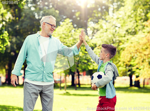 Image of old man and boy with soccer ball making high five