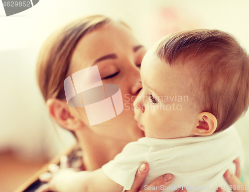 Image of happy young mother kissing little baby at home