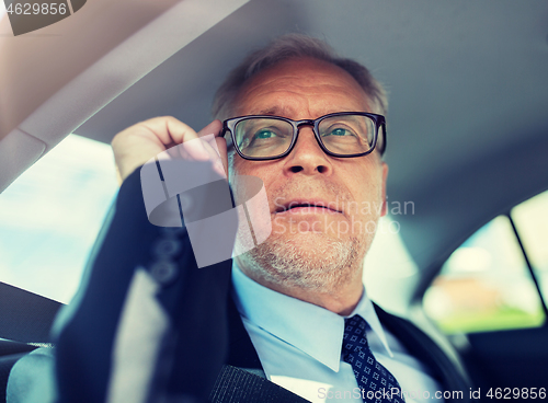 Image of senior businessman calling on smartphone in car