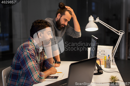 Image of creative team with computer working late at office