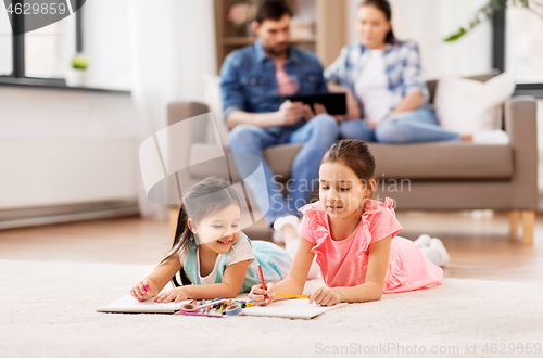 Image of happy sisters drawing in sketchbooks at home