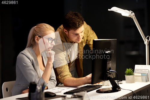 Image of business team with computer at night office