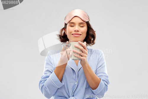 Image of woman in pajama and sleeping mask drinking coffee