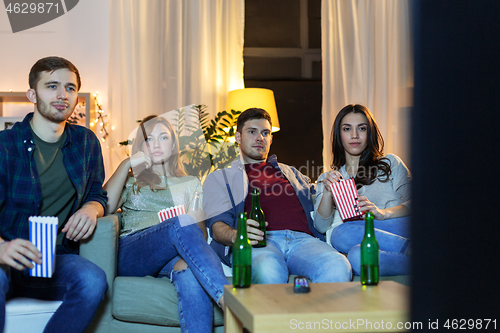 Image of friends with beer and popcorn watching tv at home