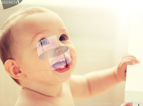 Image of happy little baby boy or girl at home looking up