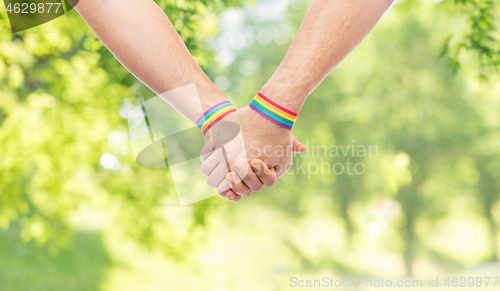 Image of hands of couple with gay pride rainbow wristbands