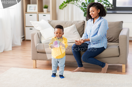 Image of mother and baby playing with ball at home