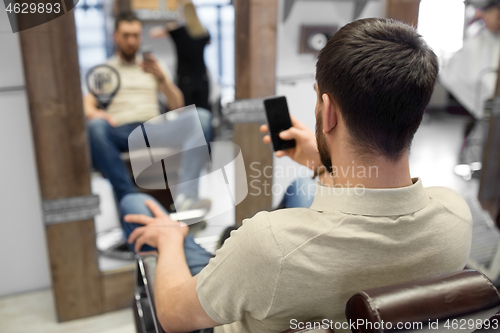 Image of man with smartphone at barbershop or hair salon