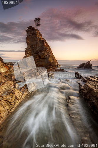 Image of Water flowing fast through narrow chasm beside seastack woth sol