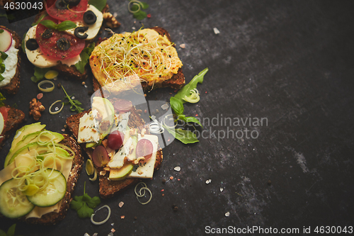 Image of Variety of healthy fresh sandwiches with different vegetables, herbs and ingredients on dark table