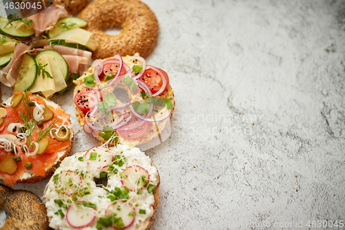 Image of Homemade Bagel sandwiches with different toppings, salmon, cottage cheese, hummus, ham, radish