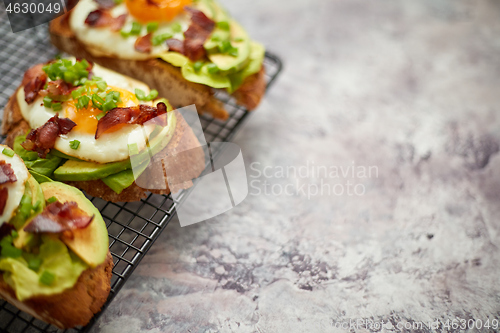 Image of Breakfast concept. Tasty delicious homemade toasts with fried egg, bacon, avocado, lettuce and chive