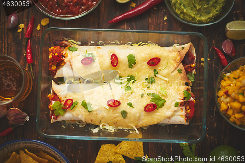 Image of Vegetable Burritos served in glass heatproof dish. With salsa, guacamole, nachos and ingredients