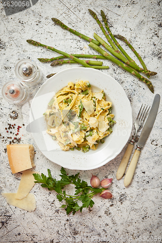 Image of Homemade tagliatelle pasta with creamy ricotta cheese sauce and asparagus served white ceramic plate