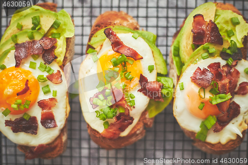 Image of Breakfast concept. Tasty delicious homemade toasts with fried egg, bacon, avocado, lettuce and chive