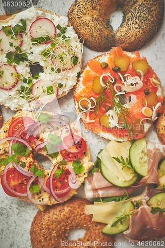 Image of Homemade Bagel sandwiches with different toppings, salmon, cottage cheese, hummus, ham, radish