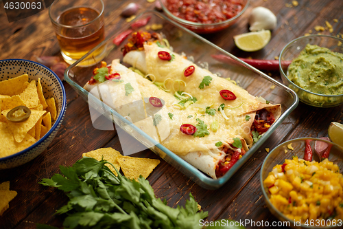 Image of Vegetable Burritos served in glass heatproof dish. With salsa, guacamole, nachos and ingredients