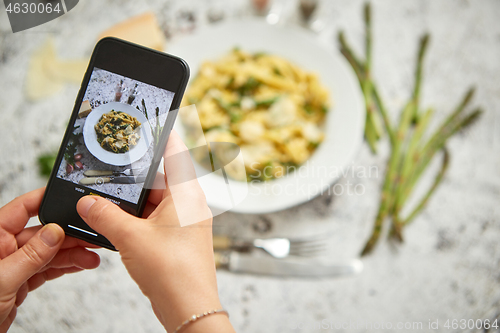 Image of Woman making a photo with a smarpthone of homemade tagliatelle pasta with creamy ricotta