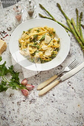 Image of Tagliatelle pasta with creamy ricotta cheese sauce and asparagus served white ceramic plate