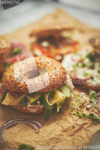 Image of Bagel sandwiches with various toppings, salmon, cottage cheese, hummus, ham, radish and fresh herbs