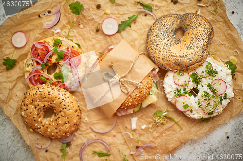 Image of Bagels with ham, cream cheese, hummus, radish wrapped in brown baking paper ready for take away