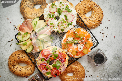 Image of Delicious Bagel sandwiches with creamy cheese, ham, hummus, salmon and vegetables