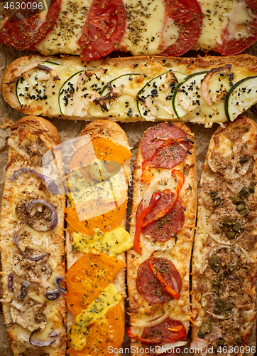 Image of Assortment of various toppings baked sandwiches. With melted che