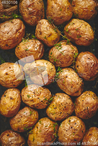 Image of Oven baked whole potatoes with seasoning and herbs in metalic tr