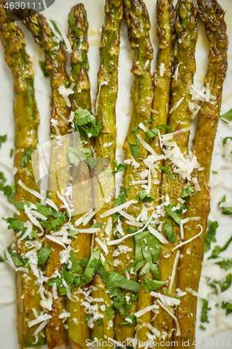 Image of Close up. Hot fresh roasted asparagus with parmesan cheese and parsley. Healthy spring food concept