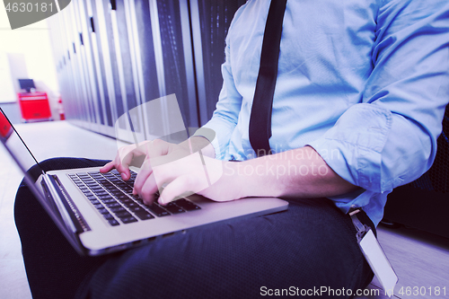 Image of engineer working on a laptop in server room