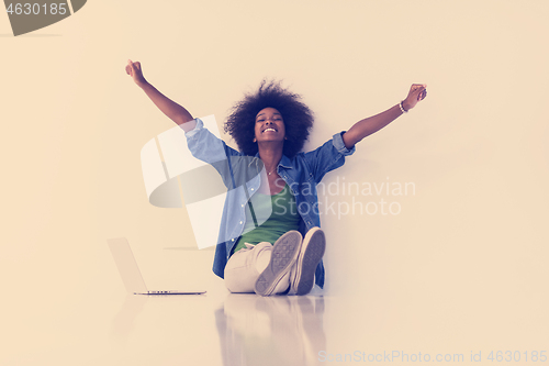 Image of african american woman sitting on floor with laptop