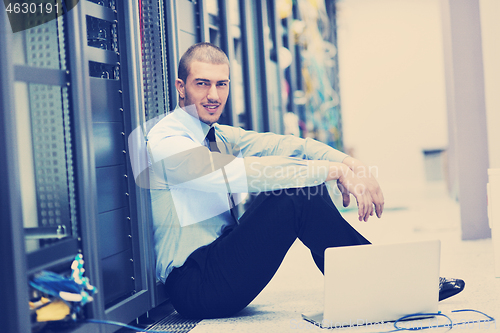 Image of businessman with laptop in network server room