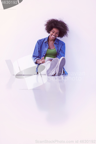 Image of african american woman sitting on floor with laptop