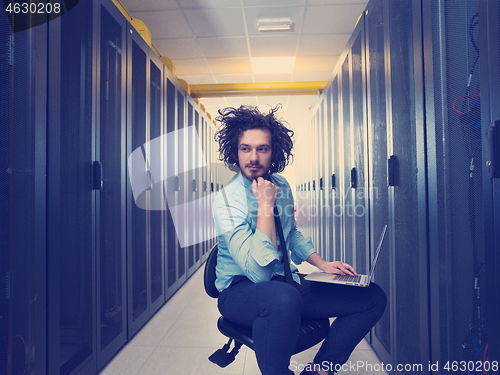 Image of engineer working on a laptop in server room