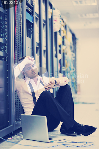 Image of businessman with laptop in network server room