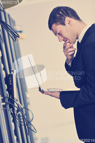 Image of businessman with laptop in network server room