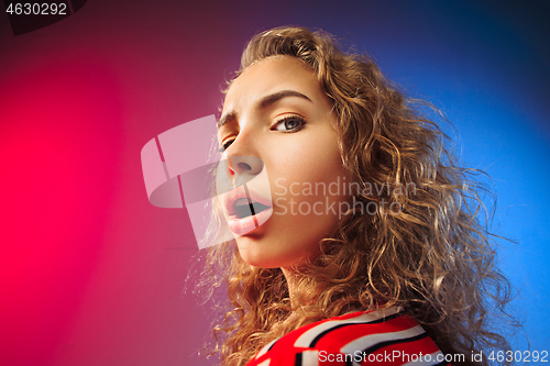 Image of The serious sad woman standing and looking at camera against colorful background.